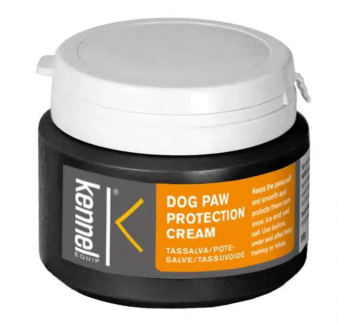 En grå och svart behållare med Kennel Equip Dog Paw Protection Cream med en orange etikett. Etiketten indikerar att krämen håller kattens tassar mjuka, släta och skyddar mot is, vägsalt, värme och grova ytor. Behållaren har ett vitt skruvlock.