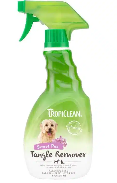 En grön sprayflaska märkt "TropiClean Sweet Pea Tangle Remover" har en bild på en glad hund. Produkten påstår sig hjälpa till att ta bort trassel, knutar och mattor och är alkoholfri och färgämnesfri. Flaskan har ett grönt munstycke och innehåller 16 fluid ounces.