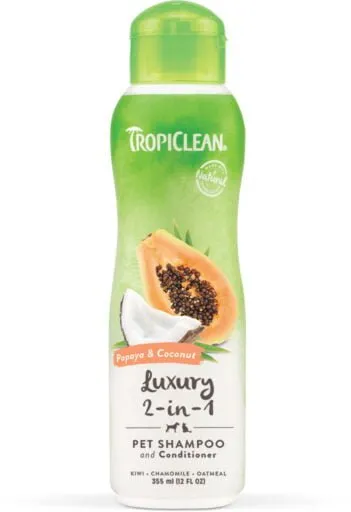 Bilden visar en flaska TropiClean Luxury 2-in-1 Pet Shampoo and Conditioner för hund och katt. Den gröna och vita flaskan med ett limegrönt lock har bilder av papaya och kokosnötskivor på framsidan, innehållande 355 ml (12 fl oz) produkt.