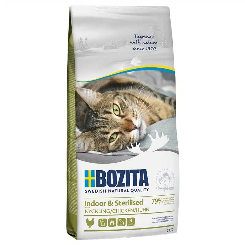 En påse Bozita Indoor & Sterilized Chicken Kattmatta 10 kg med en avslappnad tabby katt som ligger ner. Den vita väskan med gröna accenter visar texten "Kyckling/Kyckling/Huhn, 79%" tillsammans med olika produktdetaljer och ikoner.